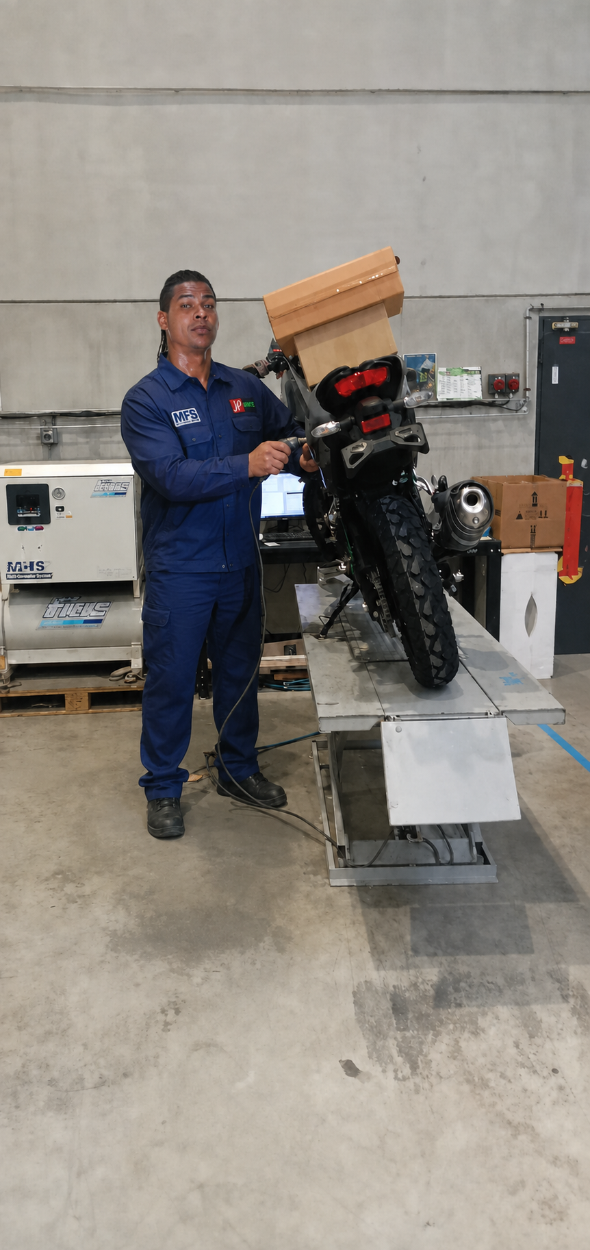 Technicien MFS en tenue bleue réalisant un gravage sur une moto dans le dépôt